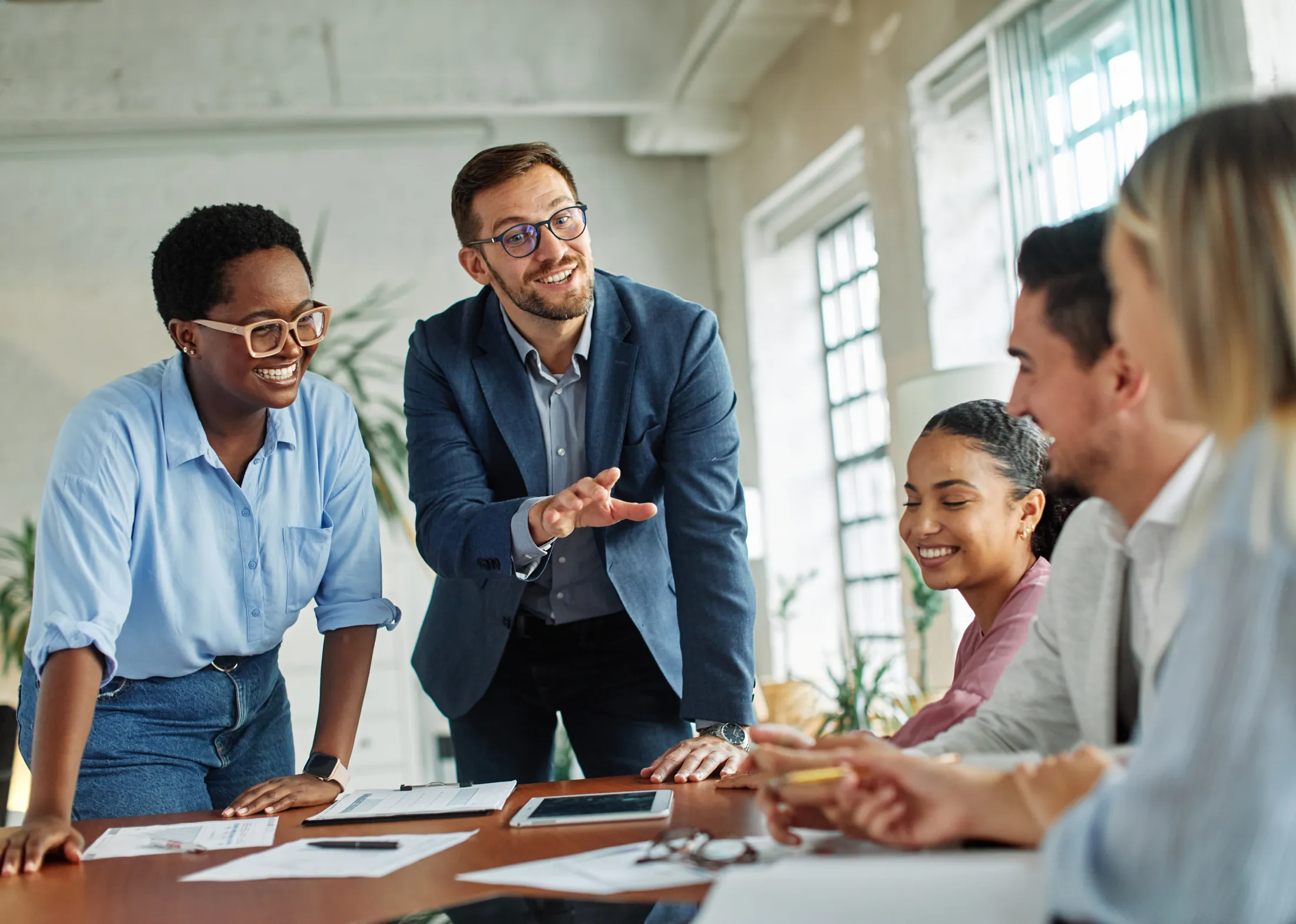 Colleagues talking and laughing around a table in a bright office